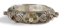 Bracelet deblij, Maroc, Anti Atlas, région de Tafraout, XXe siècle Argent niellé et émaillé vert et ocre à charnière, à décor de rosettes et perles géométriques rapportées, sur fond hachuré. Diam.: 7,5 cm Poids brut: 71 gr Voir pour d?autres exemples le catalogue d?exposition Splendeurs du Maroc, Tervuren, 1998, cat. 454 p. 285 ainsi que J. et M. R. Rabaté, Bijoux du Maroc, Aix-en-Provence, 1996, p. 59. A silver bracelet, Deblij, Morocco Tafraout area, 20th century
