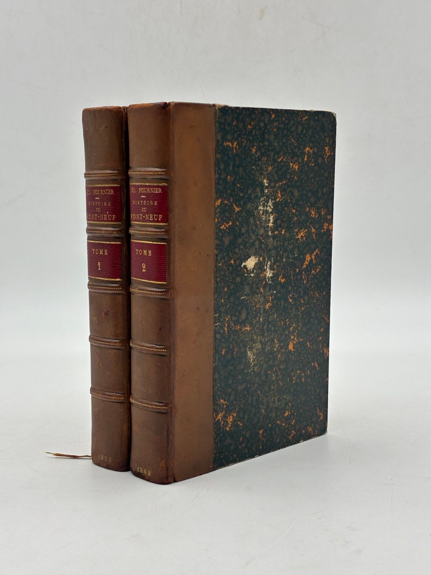FOURNIER, Édouard. Histoire du Pont-Neuf.
Edité à Paris chez Dentu en 1862.
En 2 volumes de format In douze / In-12.
Demi-basane brune. Dos à faux-nerfs soulignés d'un pointillé doré et encadrés à froid, titrage et tomaison dorés sur pièce de cuir rouge, date dorée en pied. Tranches de tête dorées. Signets conservés. Couvertures d'origines et dos conservés. Reliure de l'époque.
308 pages ; de 309 à 622 pages et 1 f.n.ch. (errata), titre imprimé en noir et rouge. 
Menus frottements, mors partiellement fendus au premier plat du tome 1, légères griffures sur les plats. Rousseurs. 

Édition originale complète en 2 volumes de cette histoire du Pont-Neuf par Edouard Fournier (1819-1880).
Ex-libris héraldique d'Alex Albrecht Sarasin Georgine gravé sur une étiquette contrecollée au contreplat. 

Bel exemplaire finement relié.