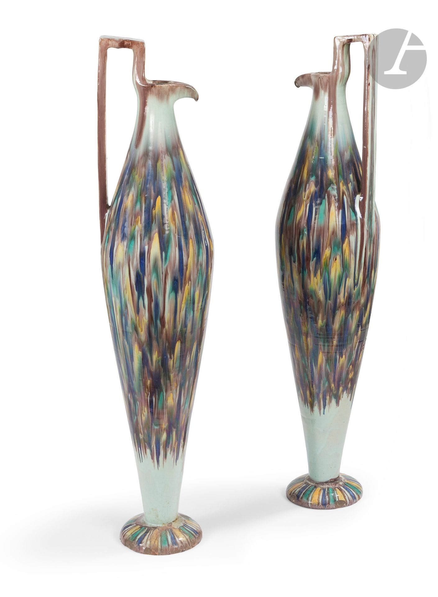 Paire de hautes aiguières chianti, Tunisie, Nabeul, atelier El-Kharraz, vers 1920-40 
Verseuses à haute panse fusiforme sur piédouche convexe, la lèvre pincée et l’anse angulaire. En faïence à décor de coulures polychromes brunes, jaunes, vertes et bleues. Estampille de l’atelier sous la base de l’une. 
Hauteur : 96 cm
Éclats, piédouches cassés, recollés et restaurés.