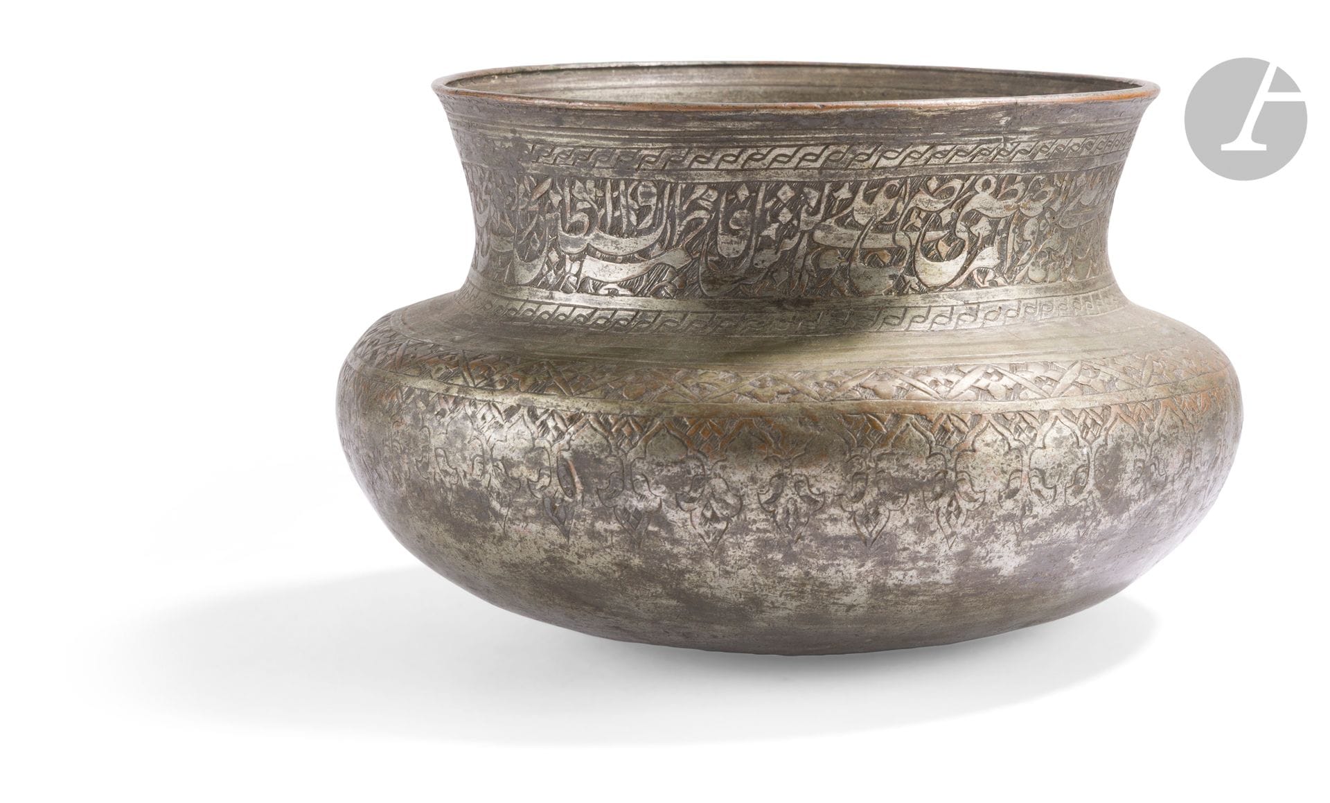 Bol tâs, Iran qâjâr, XVIIIe siècle
Bol à panse renflée surmontée d’un col cintré achevé d’une lèvre ourlée, en cuivre étamé à décor gravé. Sur le col, frise épigraphique en persan nasta’liq énumérant les quatorze Très-Purs reconnus dans le chiisme duodécimain. De part et d’autre, frise tressée, le haut de la panse gravé d’une frise de fleurons. 
Diamètre : 16,5 cm
Perforation au fond, petits chocs et usure de l’étamage.
