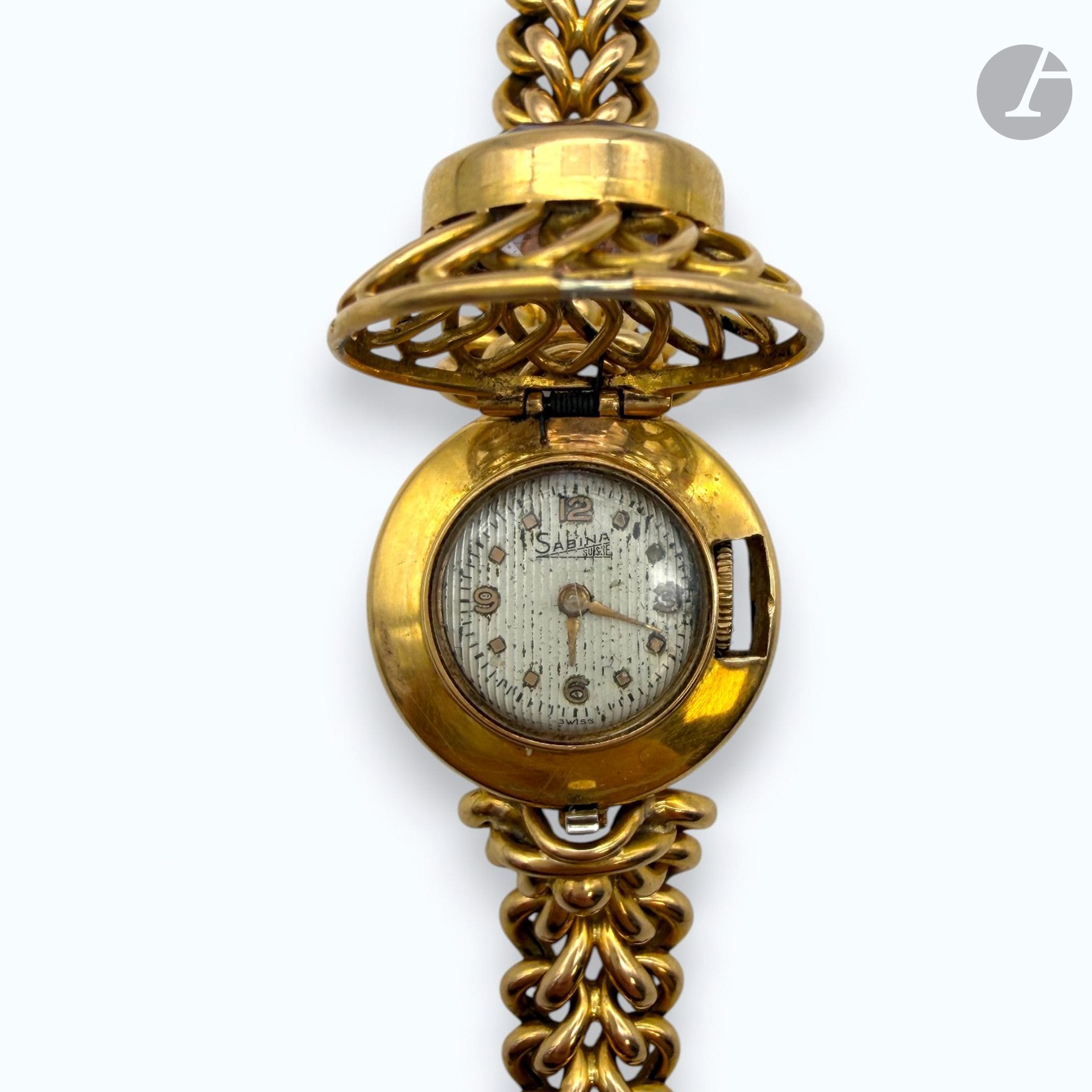 SABINA
Bracelet-montre de dame en or 750/°°°. 
La partie ouvrante sertie d'une pierre translucide violette. 
Poids brut : 38,7 g

FRAIS DE VENTE : 8% HT
