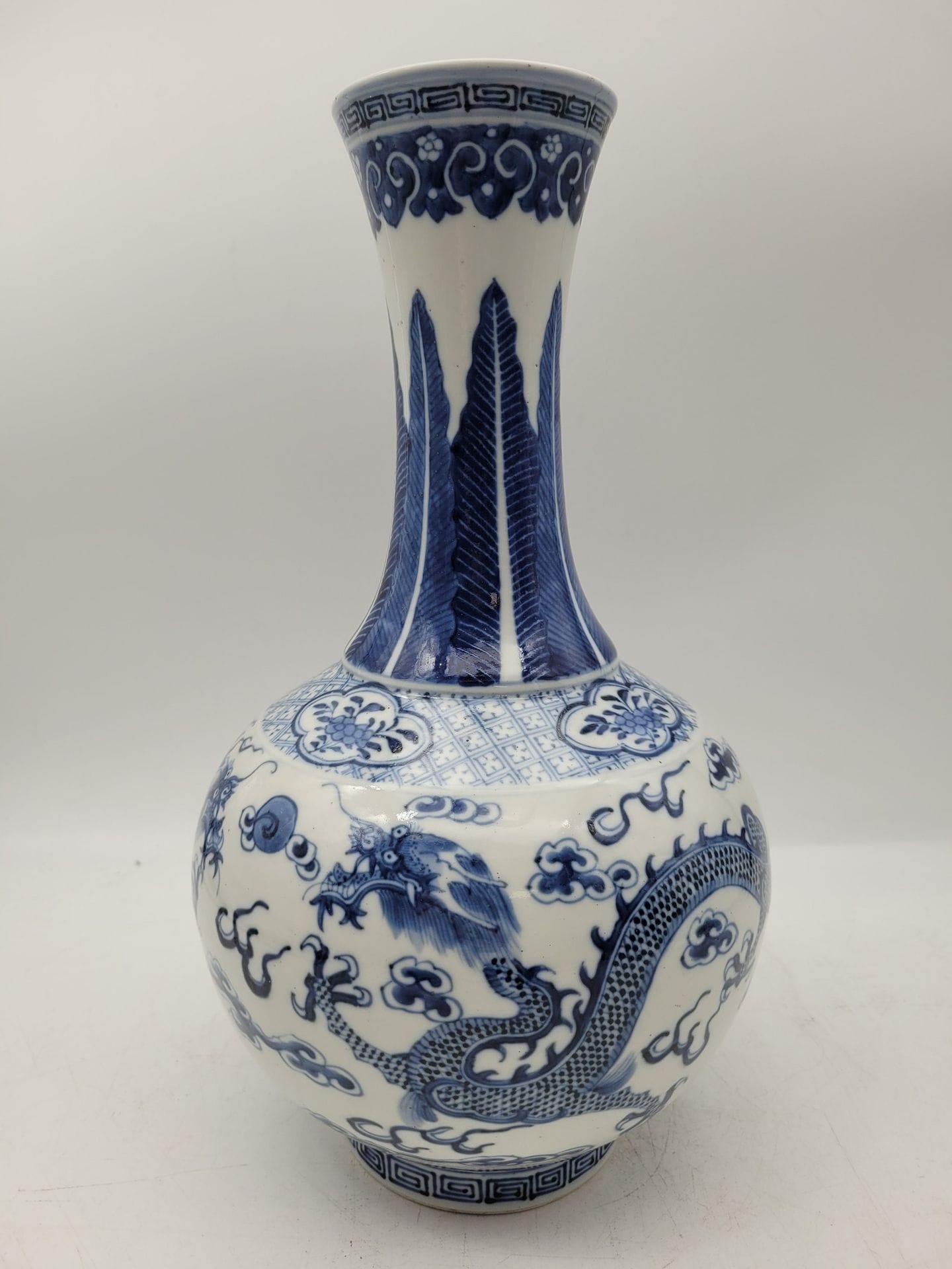 Blue-white porcelain bottle vase, China, 20th century
The globular body decorated with dragons chasing the flaming pearl, the neck decorated with water leaves, mark under the base.
Height: 23 cm
A chip under the base.