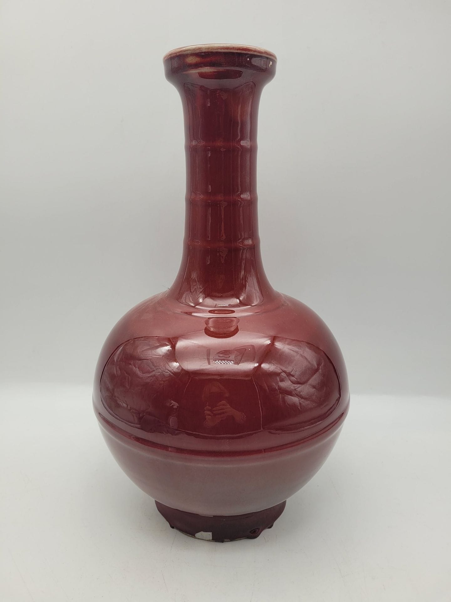 Vase à haut col en porcelaine à couverte sang de boeuf, Chine, XXe siècle
Panse ornée d'un anneau moulé en relief, col orné de 3 anneaux moulés en relief.
Hauteur : 38 cm