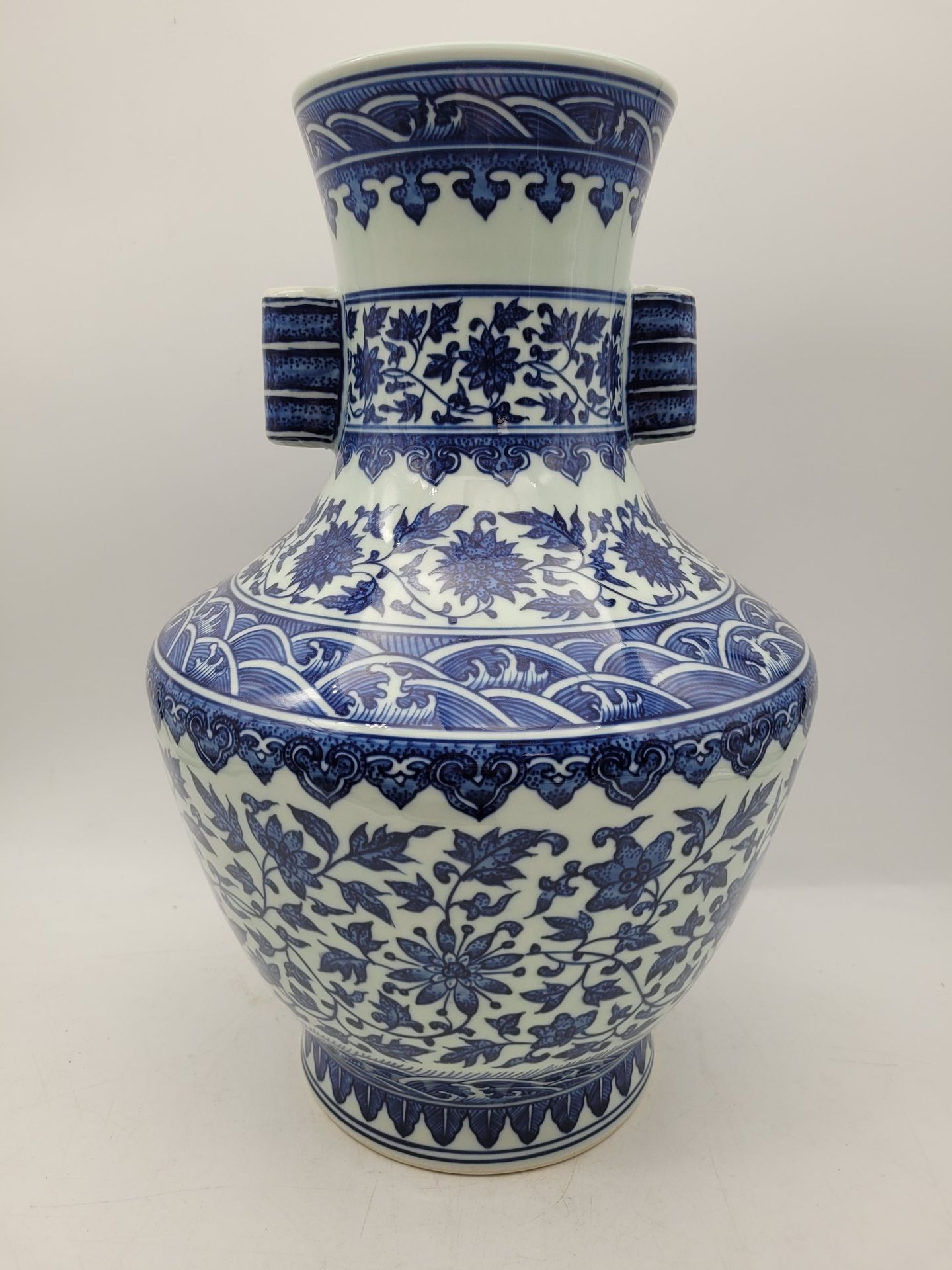 Porcelain vase with blue decoration, China, 20th century
Hu-shaped, with a slightly flared neck flanked by two tube-shaped handles, body and neck decorated with friezes of waves and flowers in foliage.
Apocryphal Qianlong mark under the base.
Height: 41 cm