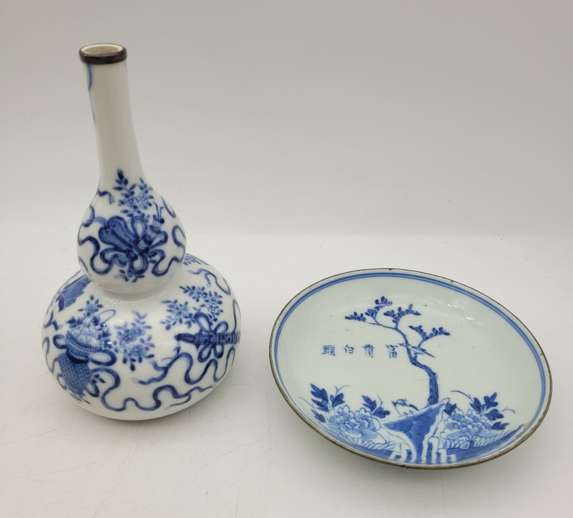 Two pieces of blue-white porcelain, China for Vietnam, 19th century
- Small double-bowl vase decorated with movable objects, rimmed neck. - Cup decorated with a bird on a rock surrounded by vegetation, inscription in the sky, ringed rim, mark under the base.
Vase height: 17.7 cm; dish diameter: 14 cm