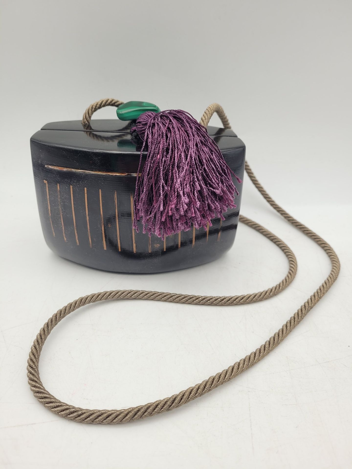Van Minh NGUYEN (1930-2014)
Sac à main en bois laqué à fond noir à décor de stries, fermoir en malachite avec un pompon, bandoulière en textile.
9,5 x 14,5 x 9,5 cm