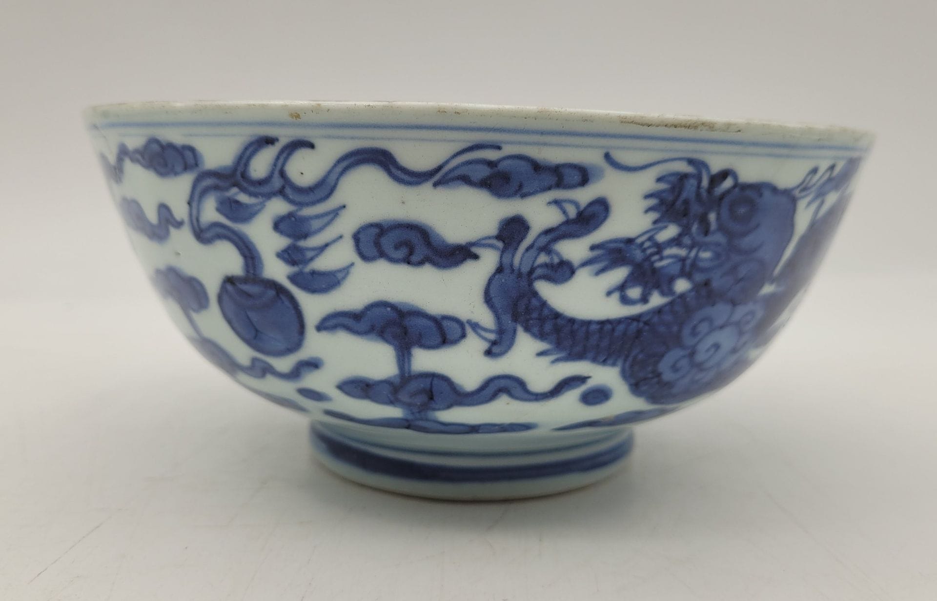 Bol en porcelaine bleu et blanc, Chine, époque Kangxi (1662-1722)
L’extérieur du bol décoré de dragons pourchassant des perles dans un ciel de nuages Tchi, l’intérieur du bol décoré d’un double cerclage au bord et d’un double cerclage au fond entourant une perle enflammée stylisée. Marque au double-poisson sous la base. 
Diamètre : 18,7 cm 
Importantes restaurations.