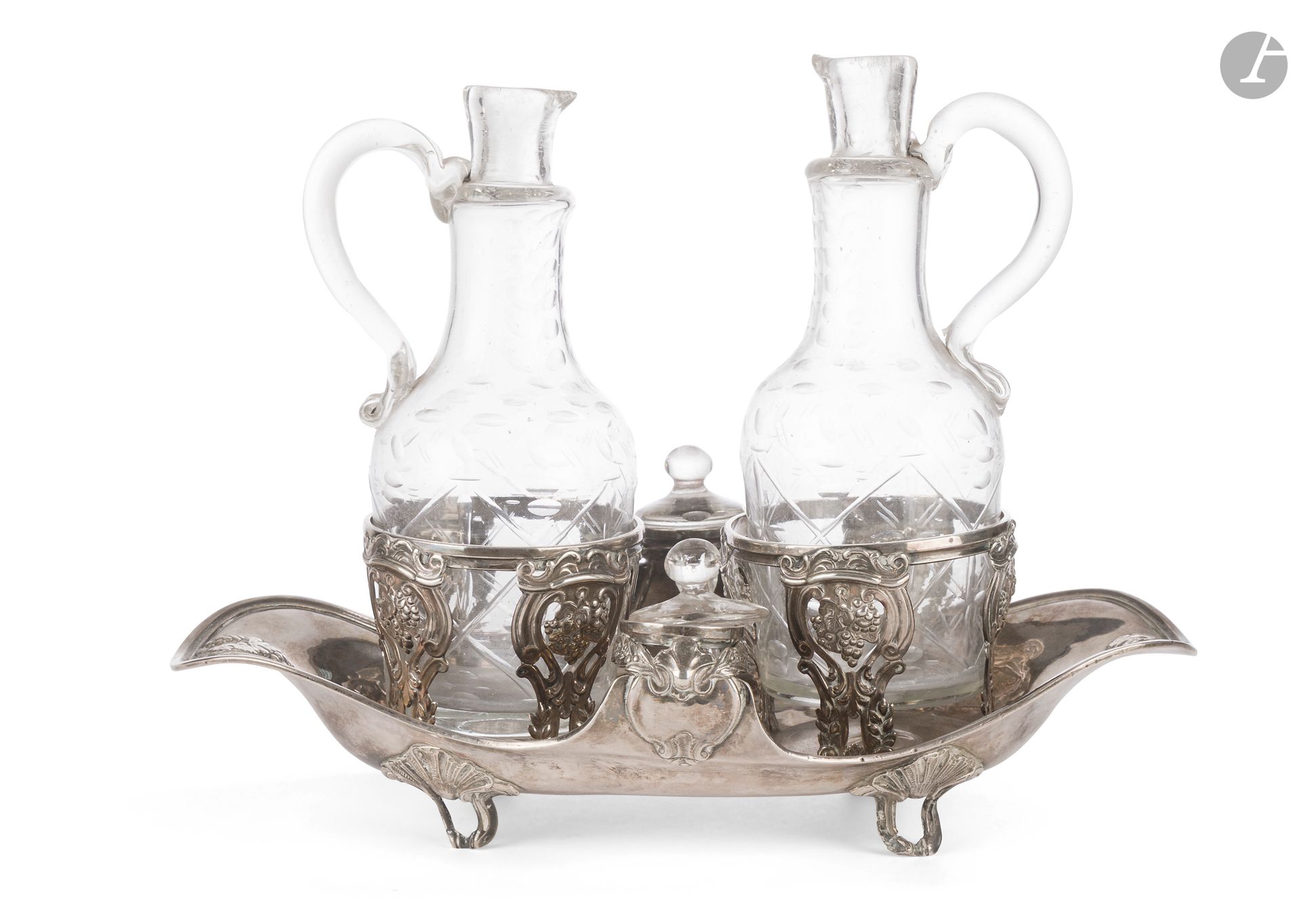 PARIS 1779 - 1780
A 950°/°° silver oil and vinegar cruet holder in the form of a quadripod tray and two glass carafes with later stoppers. Openwork embossed decoration of bunches of grapes in scrolls.
Master silversmith : René-Pierre FERRIER, received in 1775
Weight : 488 g - length : 27 cm - width : 14,5 cm