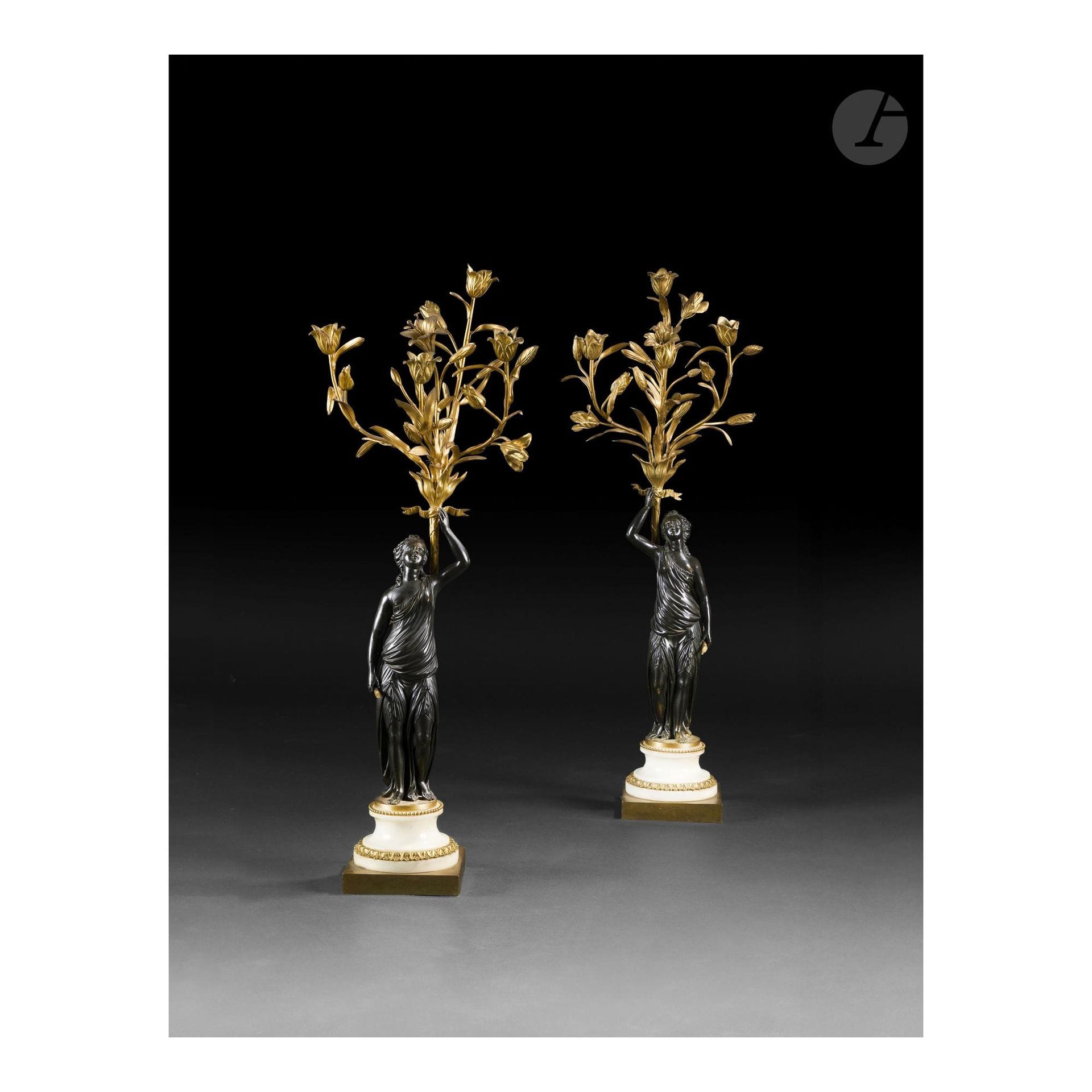 Pair of antique women's candelabra in patinated bronze and gilt bronze, with four arms of light and foliage and flower decor, the draped women's figures resting on a white marble and gilt bronze doucine base, adorned with pearl and rais-de-coeur friezes; (minor chips and restorations).
Louis XVI period
H. 82 cm