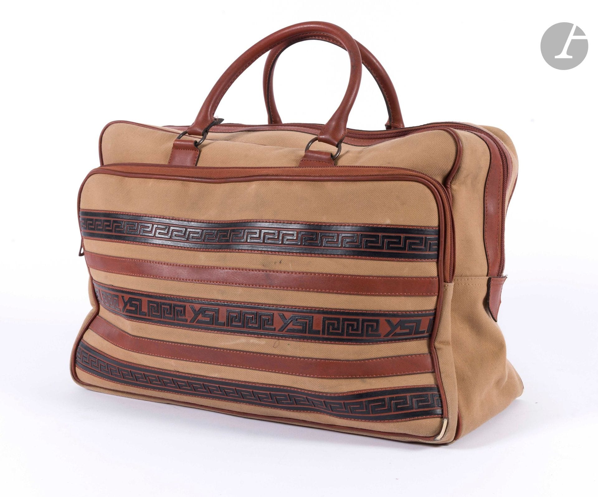 YVES  SAINT LAURENT
Sac de voyage en toile beige et cuir marron et noir à décor de frises de grecques. 50 x 33 x 20 cm (accidents aux angles, quelques traces d'usage, taches)