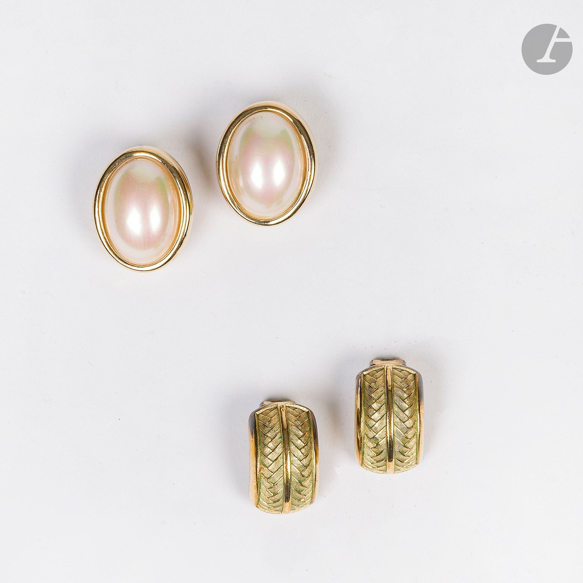 CHRISTIAN DIOR
Deux paires de clips d'oreilles en métal doré dont une ovale centrée d'une grosse perle fantaisie, l'autre à décor tressé. Signés. H : 3 et 2,5 cm