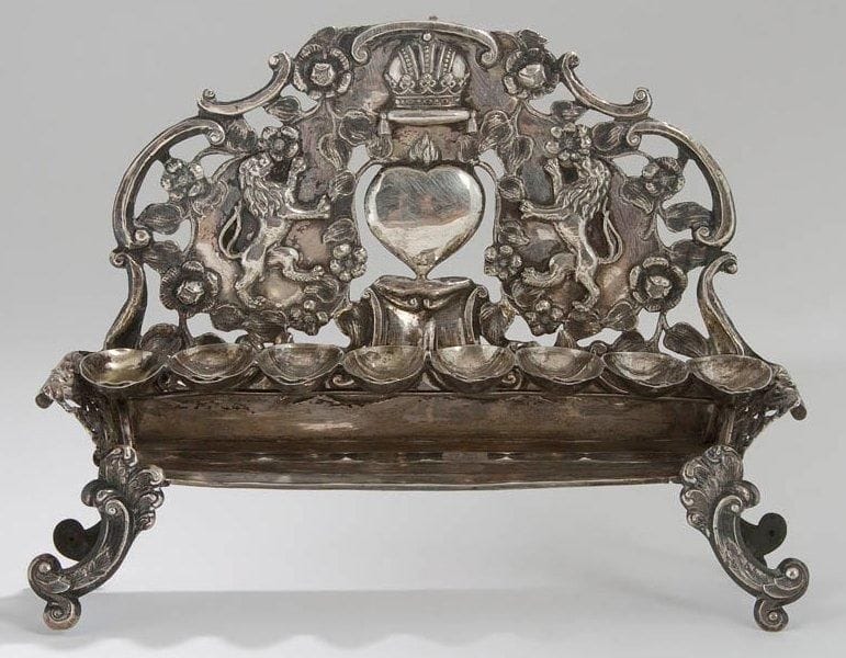 LAMPE DE HANOUCCA en argent. Godets amovibles, dosseret ajouré décoré de deux lions affrontés enserrant un coeur et surmontés par une couronne. Shamash manquant. Autriche, XIXe siècle. Poinçons autrichiens, 1880. Hauteur: 19 cm - Largeur: 25 cm - Poids: 351 g