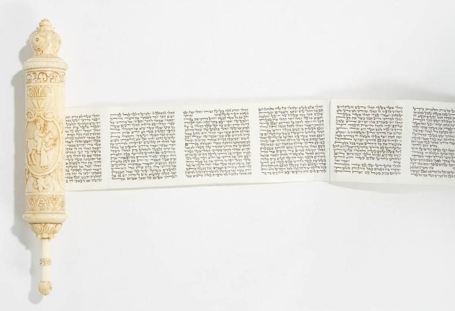 ROULEAU D'ESTHER dans son étui en ivoire. Manuscrit en hébreu sur parchemin bien conservé. Étui sculpté en réserve dans un médaillon, de la scène de l'histoire d'Esther dans laquelle Mardochée est conduit sur son cheval par Haman. Frises de fleurs et de volutes. Haut du parchemin: 6 cm - Hauteur totale 19,5 cm
