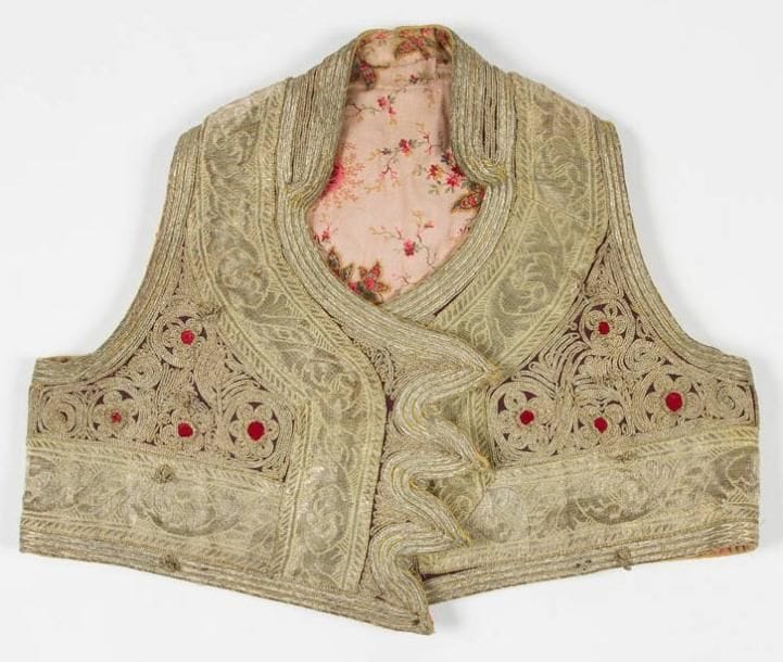 [VÊTEMENT] Veste d'enfant de cérémonie en velours et cannetille dorée. Intérieur en coton à motifs floraux. Tunisie, XXe siècle. Manquent les boutons. Hauteur: 32 cm - Largeur aux épaules: 26 cm