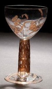 RENE LALIQUE (1860-1945)
Vigne, modèle créé en 1912, supprimé du catalogue en 1928 et non repris après 1947 Coupe haute en verre soufflé moulé pour la paraison et moulé pressé pour la jambe et la base. Décor en creux et en relief repris en ciselure et rehaussé entièrement à l?émail brun. Une infime égrenure en pourtour de la bordure. Hauteur: 17,8 cm Bibliographie: «R. Lalique, catalogue raisonné de l?oeuvre de verre» par Félix Marcilhac. Éditions de l?amateur. Paris 2004. Modèle identique reproduit page 807 et référencé sous le numéro 3761.