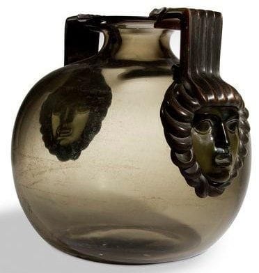 RENE LALIQUE (1860-1945)
Cluny dit aussi Deux masques et anses en bronze, modèle créé le 7 septembre 1925, non repris après 1947 Rare et exceptionnel vase en verre fumé soufflé moulé présentant, en applications, deux masques de Médusa en verre moulé pressé, collés à chaud et achevés en un polissage évoquant une patine antique. La monture, formant anses et figurant la chevelure de serpents des deux représentations mythologiques, est exécutée en bronze finement ciselé et patiné brun sombre nuancé. Un infime cheveu au départ d?une fixation. Signé R. LALIQUE, gravé sous la base. Hauteur: 26 cm Bibliographie: «R. Lalique, catalogue raisonné de l?oeuvre de verre» par Félix Marcilhac. Éditions de l?amateur. Paris 2004. Modèle identique reproduit page 430 et référencé sous le numéro 961.