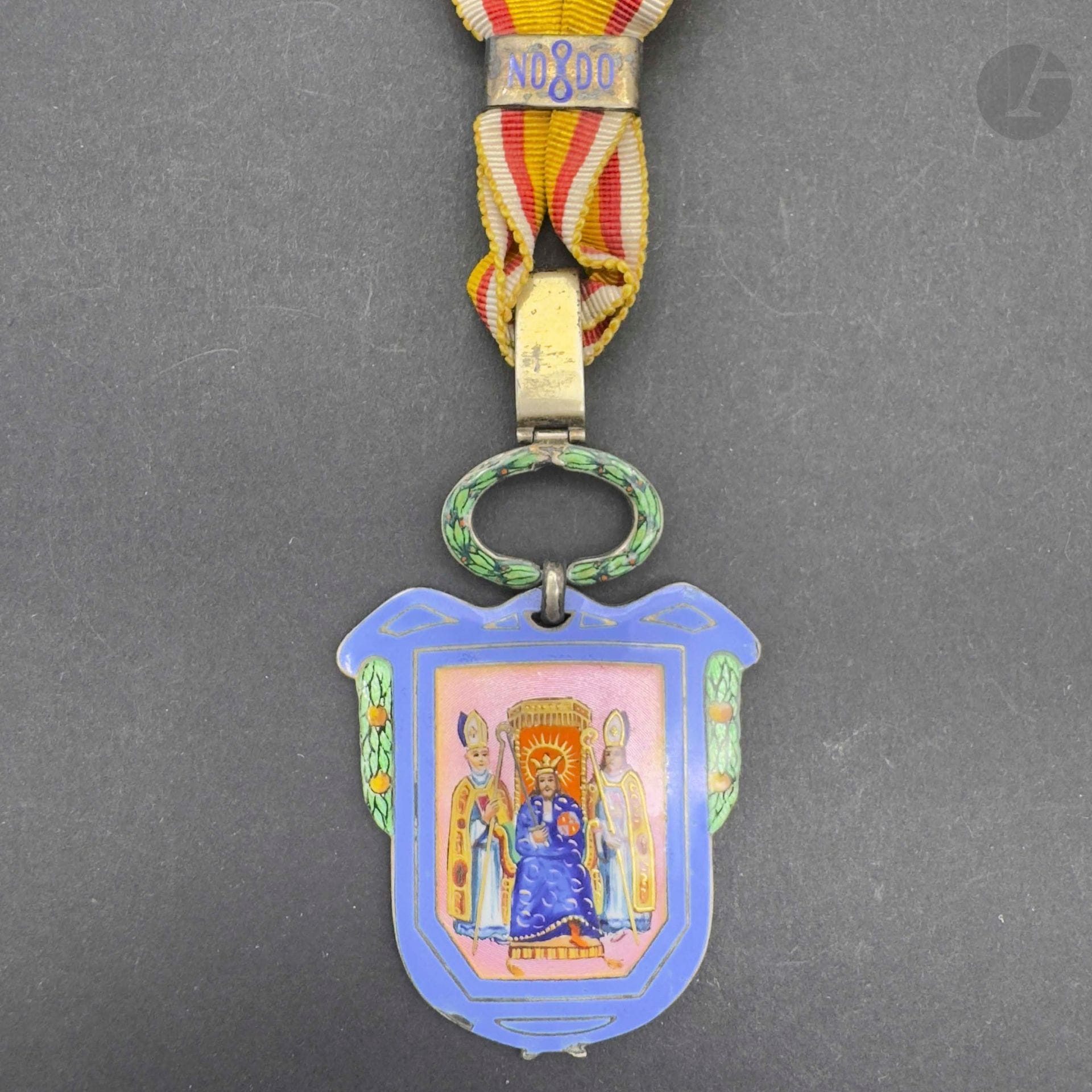 ESPAGNE 
Insigne de conseiller de la mairie de Séville. 
En vermeil et émail sous couronne de laurier. Fin ruban à bague émaillée et passant avec poinçon de titre 935. Fin ruban. 
51 x 35 mm - Poids brut: 21,90 g 
T.T.B. (Petit éclat).