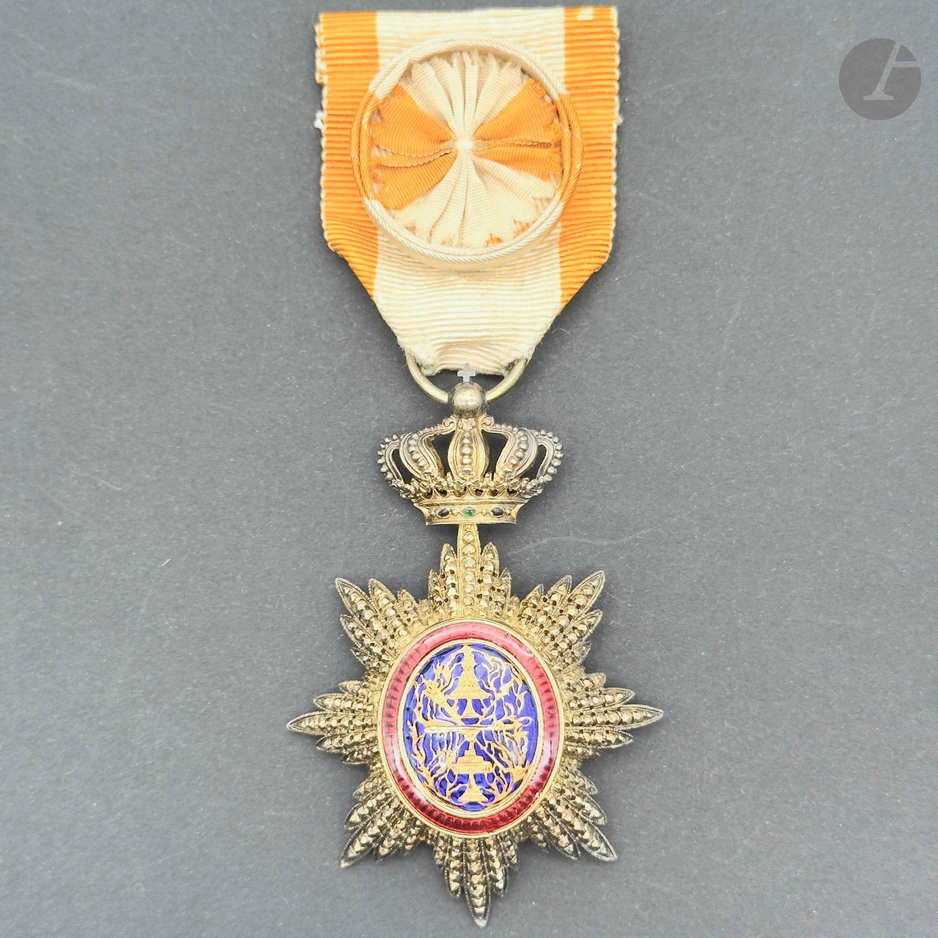 CAMBODGE 
ORDRE ROYAL DU CAMBODGE 
Étoile d’officier en vermeil et émail, centre en or émaillé. Ruban cousu à rosettes blanches et orange. 
72 x 48 mm - Poids brut: 23,8 g 
T.T.B. à SUP.
Provenance : Collection du général Chollet