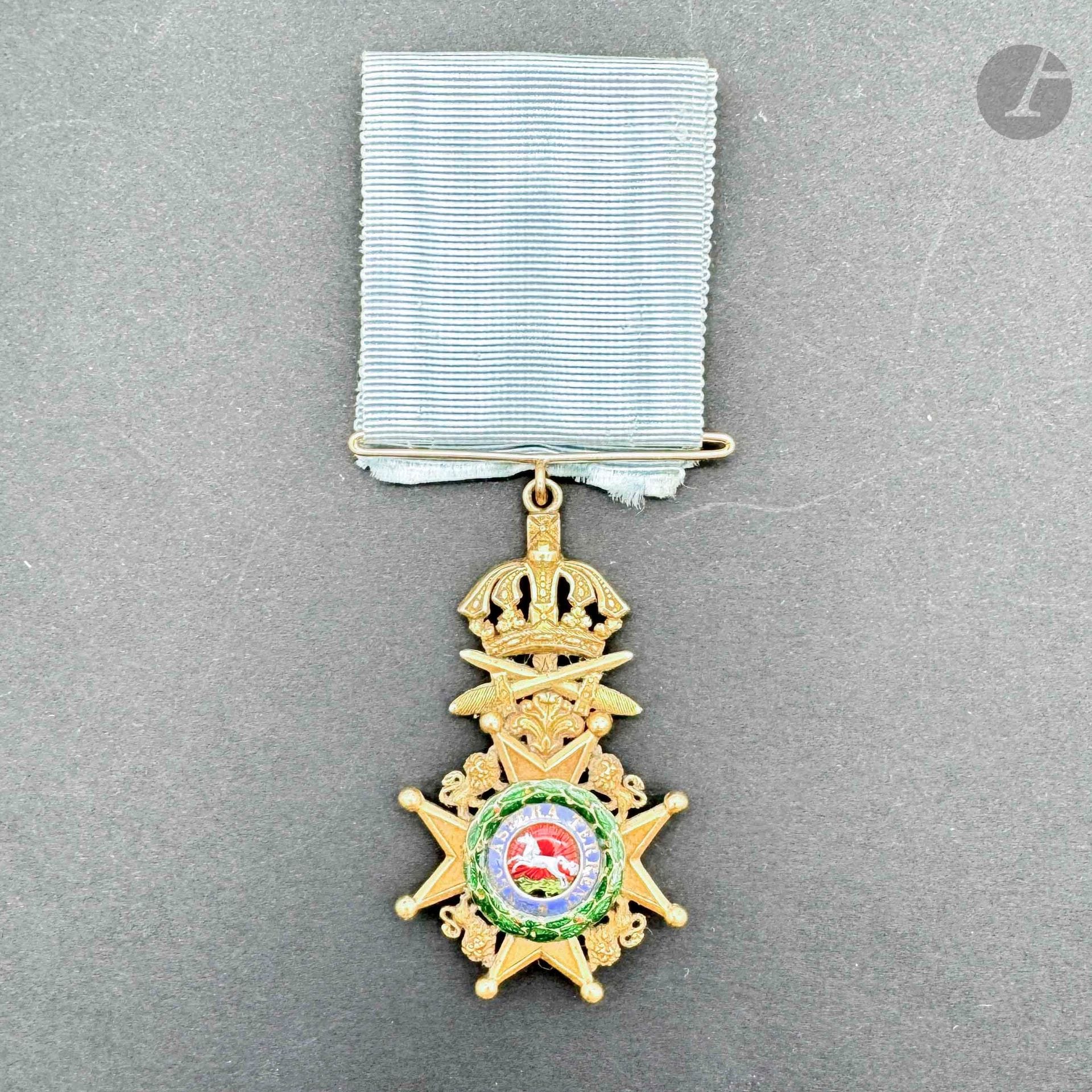 ALLEMAGNE - HANOVRE
ORDRE DES GUELFES 
Croix de chevalier à titre militaire avec glaive en or. Le centre rayonnant en émail peint (infimes éclats et petits manques à la couronne de laurier). Ruban avec large passant en or. 
59 x 35 mm - 16,6 g
T.B. à T.T.B. Vers 1830
Provenance : Collection du général Chollet