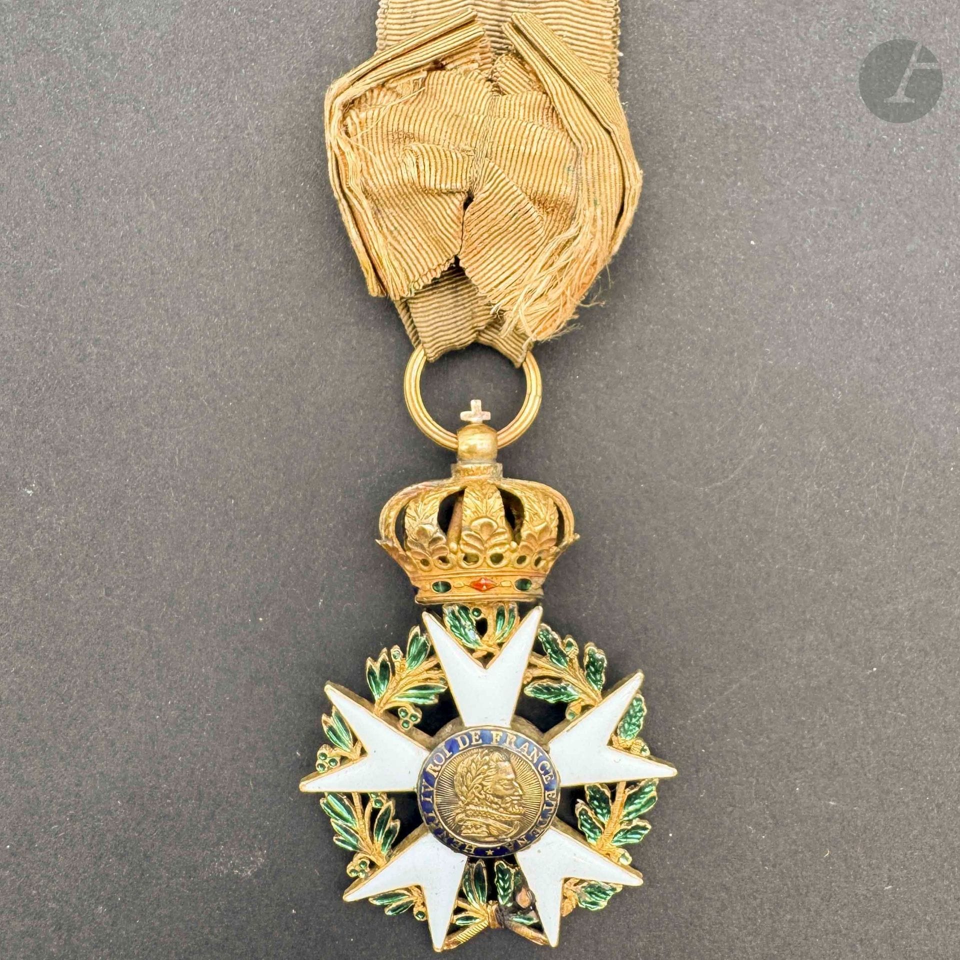 FRANCE 
ORDRE DE LA LÉGION D’HONNEUR 
Aigle d’or du 3e type d’époque Premier Empire modifié Restauration. 
En or et émail (restauration par rivet en bas de la couronne de feuillages, une griffure à l’émail blanc). Centres au profil d’Henri IV à grosse tête sur fond rayonnant et aux trois fleurs de lys sur fond strié.
Anneau cannelé avec poinçon au coq (1809-1819). Ruban à bouffette, d’époque, décoloré, avec reste de passant d’attache. 
60 x 41 mm - Poids brut: 21 g 
T.B.