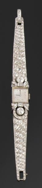 Montre bracelet de dame en or gris, cadran carré, fond satiné, index pointé de quatre diamants, les anses en boucles serties de diamants, le bracelet articulé entièrement pavé de diamants dans des motifs en «écailles de poisson». Mouvement signé UTI. Vers 1935. Poids brut: 44 g (mouvement à réviser)