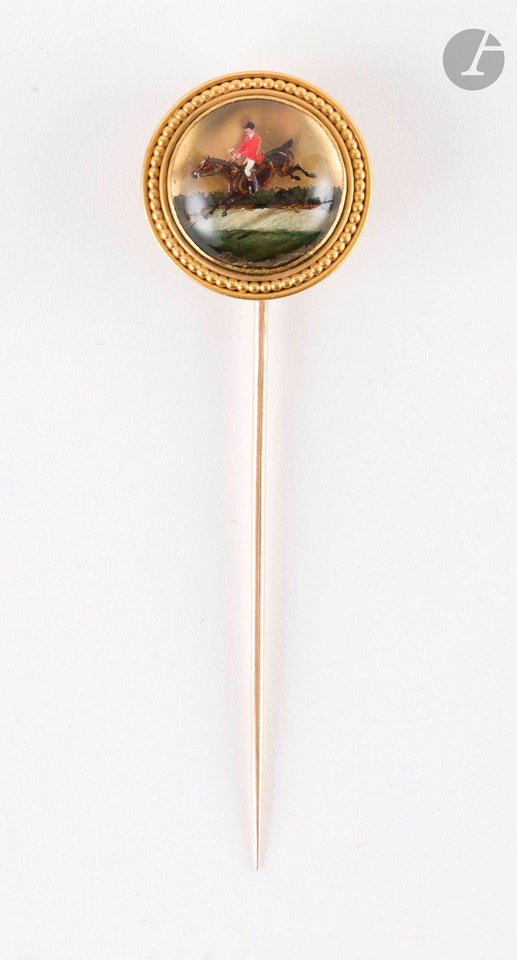 Epingle de revers en or 18K (750), sommée d'un verre Essex orné d'une scène de chasse à courre. Diamètre : 2,3 cm environ. Poids brut : 8,6 g (accident)