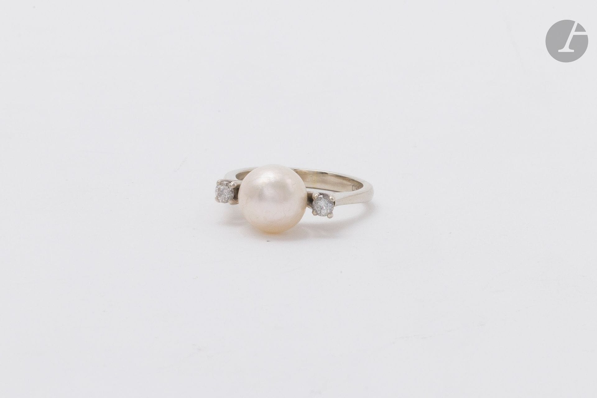 Bague en or gris 18K (750), ornée d'une perle de culture épaulée de diamants de taille brillant. Tour de doigt : 52. Poids brut : 4,3 g