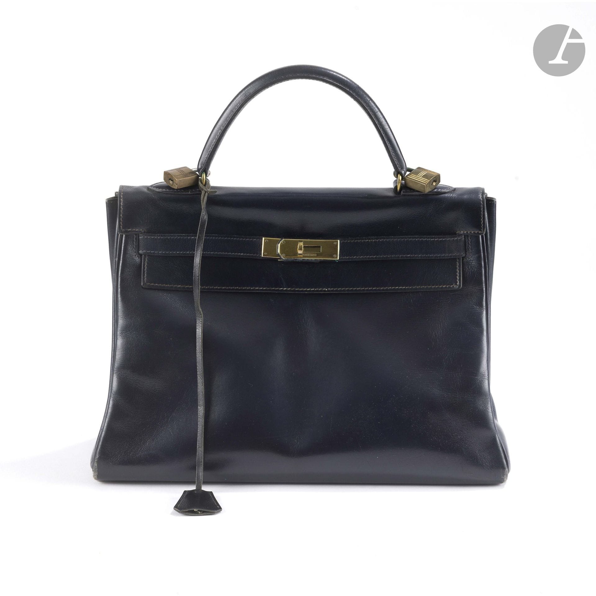 HERMÈS PARIS
Vers 1965
Sac KELLY 32 RETOURNÉ en box marine, garniture en métal doré, cadenas et deux clés sous clochette
32 x 23 x 12 cm
(usures, pertes de dorure, un cadenas supplémentaire sans clé)