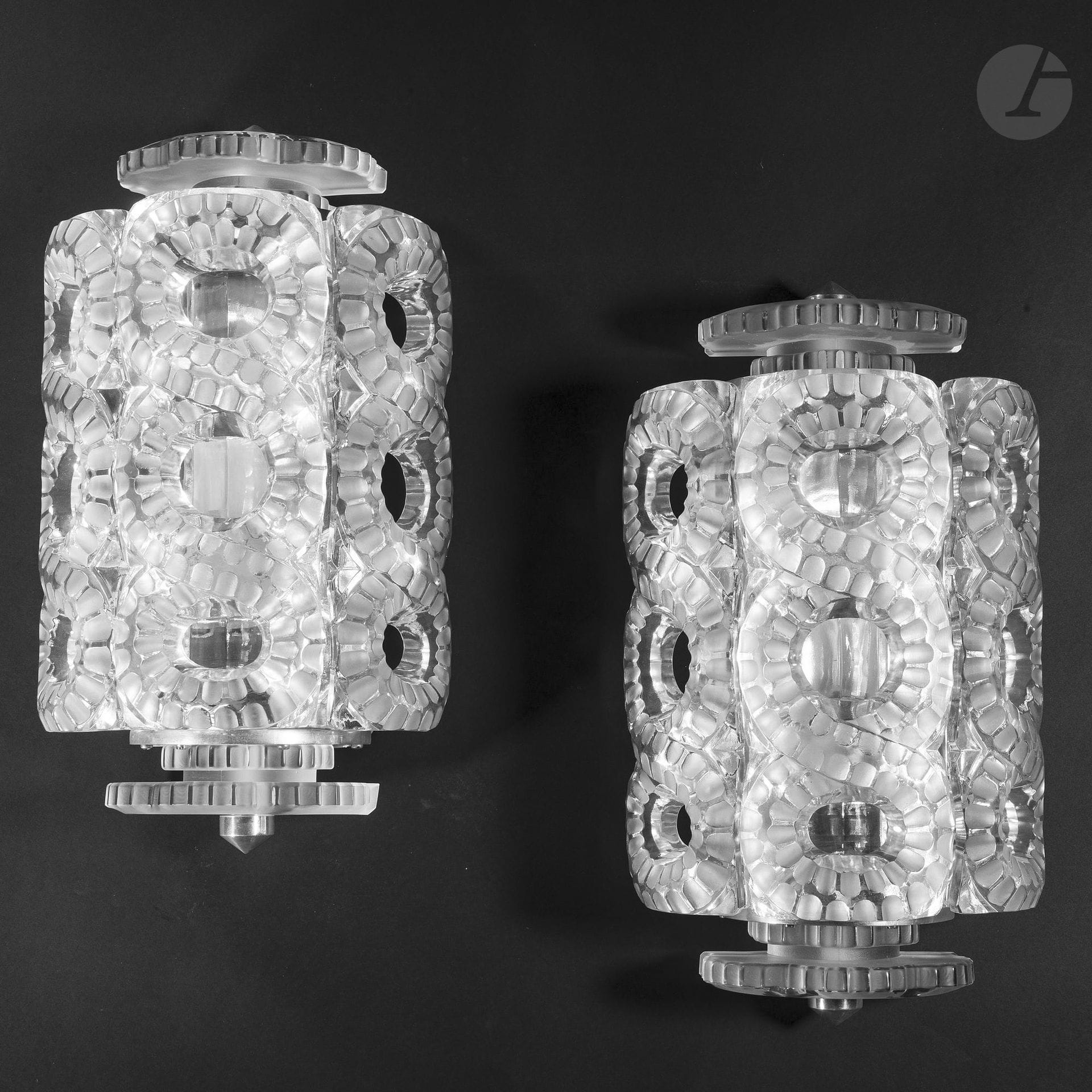 MARC LALIQUE (1900-1977) & MAISON LALIQUE
Séville, le modèle créé en [1947]
Paire d’appliques. Épreuves en cristal moulé-pressé et, en partie, satiné. Les platines murales en aluminium. Un petit choc et manque au percement recevant la fixation d’une des ailettes; totalement invisible une fois l’élément monté. Chaque applique signée LALIQUE sur une platine de réception. H.42cm

Bibliographie:
Mobilier et Décoration – Décembre 1949. Une applique de la série Séville de Marc Lalique reproduite page 25, dans un article titré «Lalique ou la poésie du verre» sous la plume de P.Sentenac.