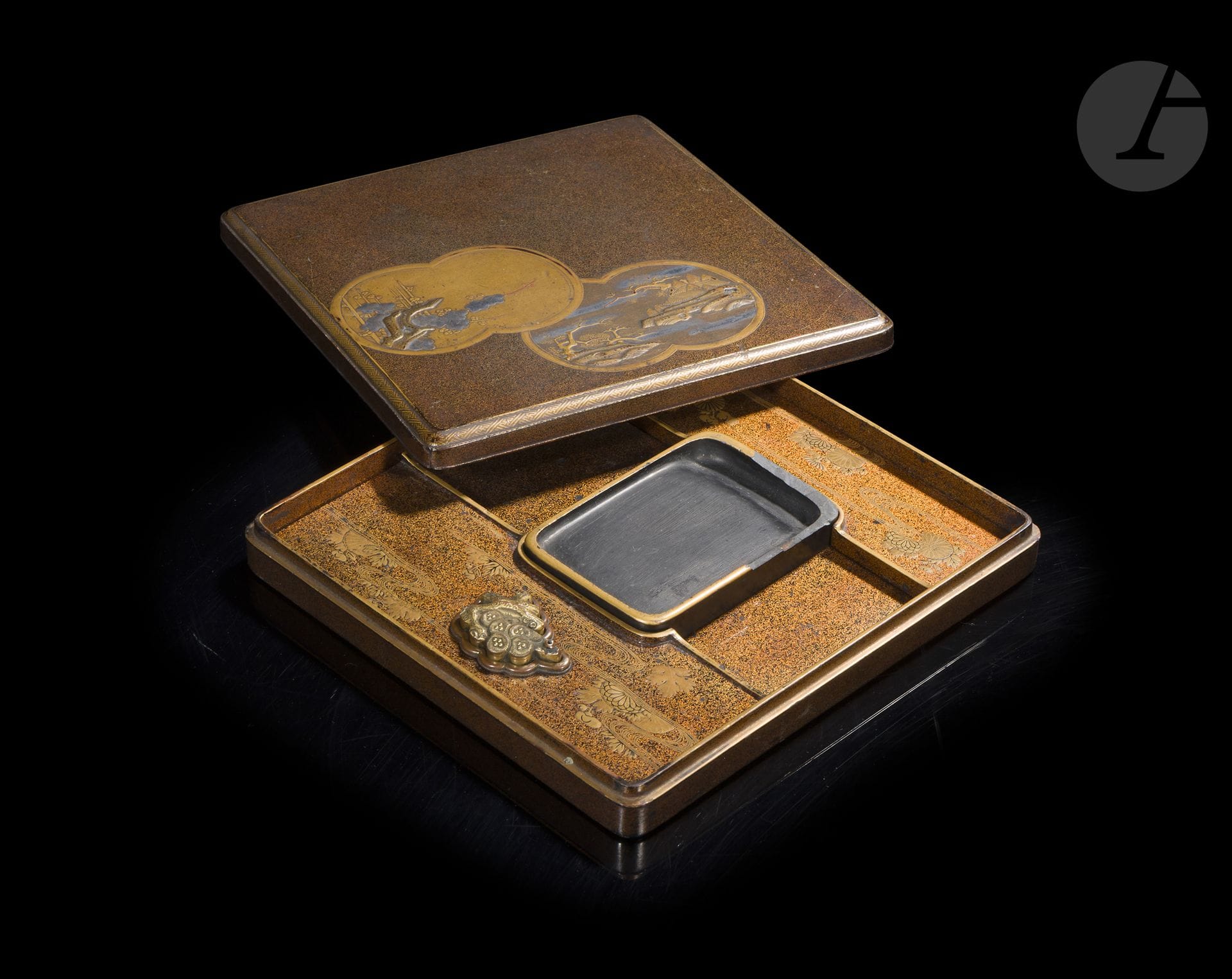 Suzuribako (writing box) made of lacquered wood, Japan, Edo period, 18th century
A rectangular box with slightly rounded corners, decorated with gold and silver taka maki-e, hiramaki-e, kirikane, and nashiji on a brown lacquer background speckled with hirameji. The lid is adorned with two adjacent cloud-shaped inlays. The first features a plum tree in bloom; the second, a mountainous landscape enlivened by pavilions, pine trees, bamboo, and plum trees rendered in shades of gold and silver. The rim is outlined with a geometric frieze featuring a swastika motif known as sayagata. The top features a design of winding rivers, chrysanthemums, and foliage rendered in gold maki-e on a nashiji background, while the central compartment houses a black stone inkstone (suzuri), framed by a gold-lacquered mount. Engraved beneath the suzuri is the inscription: 御硯屋 禁裏様 中村弥右衛門—“suzuri workshop—for the Imperial Court—Nakamura Yaemon.” The suiteki is made of gilded copper alloy with an uchidashi decoration of a pine tree. The interior and underside are finished in nashiji lacquer.
20 x 18.5 cm
Signs of wear, damage to the corners, lacquer loss, and damage to the edge of the suzuri.