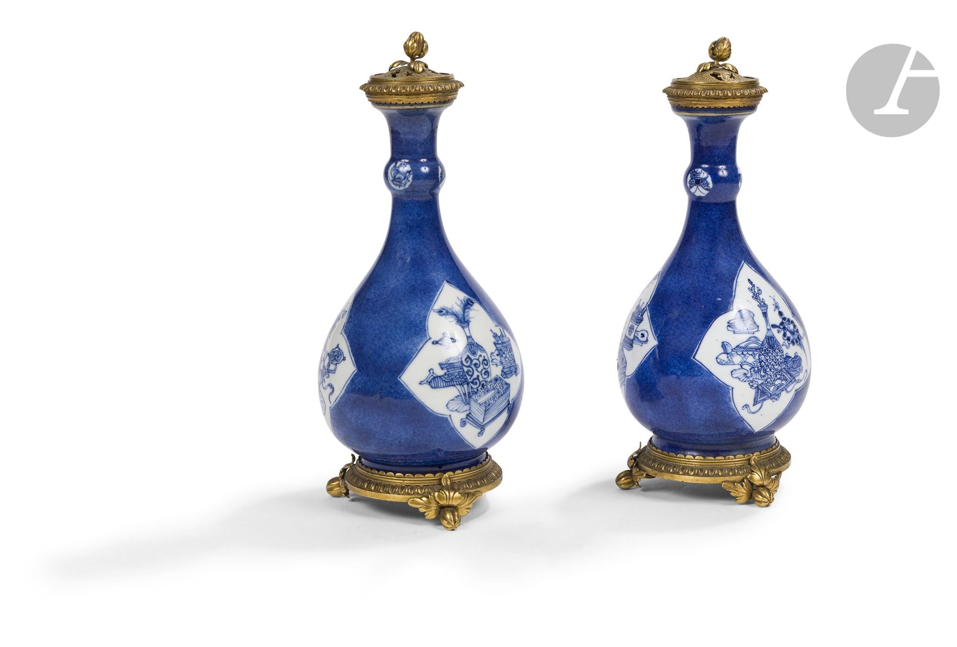 Paire de vases en porcelaine bleu poudré et bleu blanc, Chine, XVIIIe siècle, montés en brûle-parfums en Europe
Les vases de forme bouteille à fond bleu poudré sont à décor émaillé en bleu de quatre réserves quadrilobées ornées de divers objets de lettrés et de bon auspice (bitong, livres, nécessaire pour l’encens, jeu de plateau, vases, rouleaux, sceptre ruyi…). Trois petits médaillons renfermant un papillon décorent un petit renflement situé au milieu des cols. Les vases ont été montés en alliage de cuivre en Europe pour former des brûle-parfums. Ils reposent sur une base tripode et les cols cerclés sont munis d’un petit couvercle ajouré.
Hauteur : 27,5 cm

Provenance :
Château de Ternant.