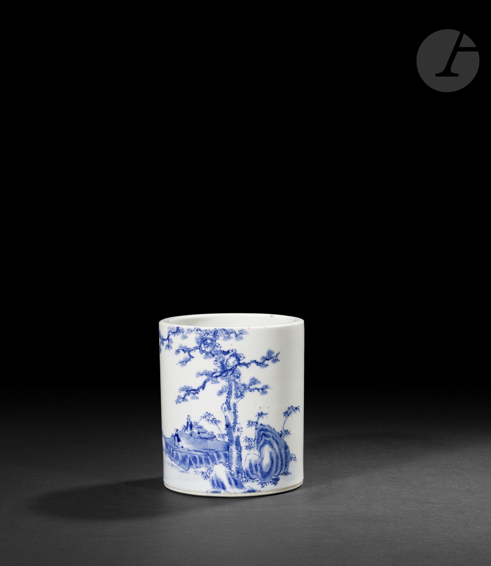 Blue-and-white porcelain brush holder, China, Kangxi period (1662–1722)
Cylindrical in shape, made of porcelain glazed in blue under the glaze. The main design depicts a vast lakeside landscape animated by scholars seated on a rocky mound, dominated by an imposing, gnarled pine tree with spreading branches. In the background, a boat glides along a river while a fisherman casts his line. A poetic inscription accompanies the scene. The inscription can be transcribed as follows: 对坐清谈世事 间看浅水行舟 - “Seated face to face, we calmly discuss worldly affairs, while watching a boat glide across the shallow waters.” Below is a rare four-character seal mark, 康熙年製 (Kangxi nian zhi) – “Made during the Kangxi reign,” inscribed in blue underglaze.
Height: 14.5 cm; diameter: 12.5 cm

The decoration, like the accompanying poem, is reminiscent in both subject matter and style of the so-called “Hue blue” wares produced for the Vietnamese market. Although, to the best of our knowledge, no brush pot bearing a “Kangxi nian zhi” mark in Huê blue is currently documented, this origin remains a possibility.
