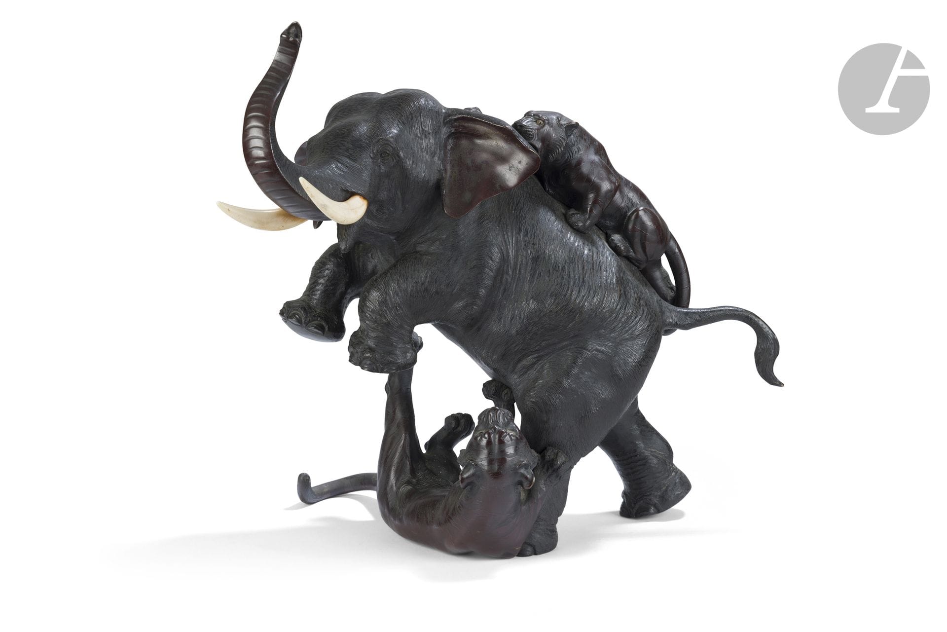 Okimono en alliage de cuivre, Japon, époque Meiji (1868-1912)
Représentant un éléphant attaqué par deux tigres, il est recouvert d’une double patine brune et chocolat. Les défenses sont en ivoire et les yeux des tigres en sulfure. Sous le corps du pachyderme une signature à deux caractères sigillaires Mitsumoto - 光元.
Hauteur : 39 cm 
Accident à la queue d’un des deux tigres, une défense détachée.