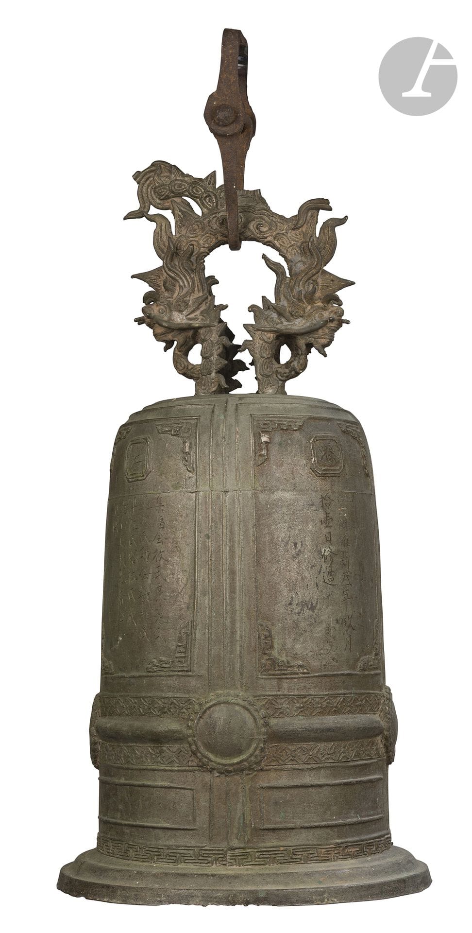 Đại Hồng Chung temple bell, Vietnam, late 19th–early 20th century 
Made of bronze with a brown and verdigris patina, cylindrical in shape and slightly flared toward the base, resting on a wide circular base. The body is divided by vertical and horizontal bands and features, in its upper section, a series of panels adorned with geometric motifs containing characters. The lower section is accented by a frieze of Greek frets. A wide horizontal ridge, punctuated by raised circles designed to bear the blows of the clapper or mallet, is framed above and below by two friezes featuring qibao motifs. Several vertical panels bear inscriptions chiseled in Sino-Vietnamese characters. The first reads: “During the imperial dynasty, the third year of Duy Tân, the ninth month, the eleventh day, made/repaired.” The second is a dedicatory inscription by donors. The upper section is surmounted by a large openwork suspension device formed of two facing dragons, above which a design of stylized clouds unfolds. An antique metal mount, heavily oxidized, is attached to the side of the suspension device. 
Height: 56 cm
Damage upon acquisition.