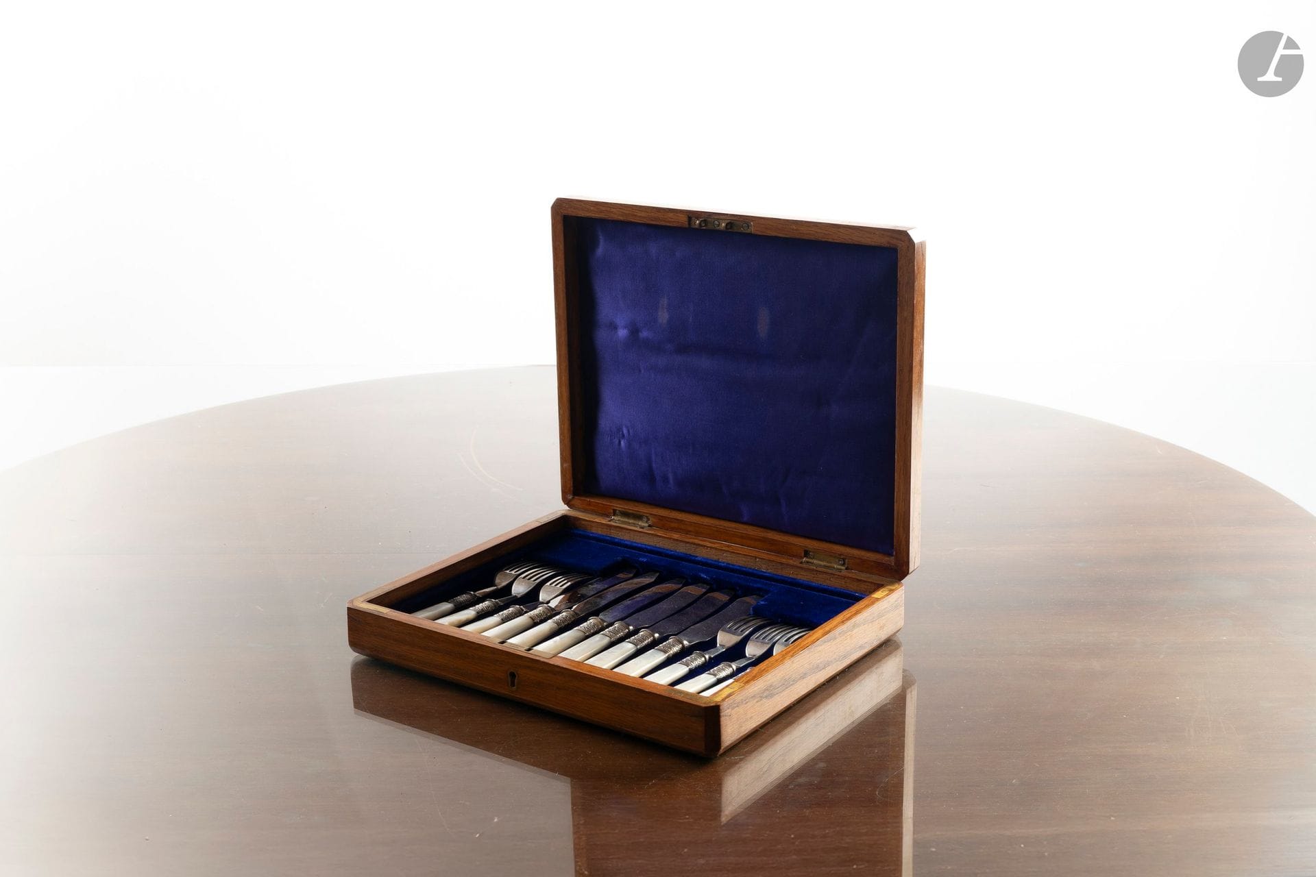 Service à poisson à manche en nacre et lame en métal argenté comprenant six fourchettes et six couteaux dans un coffret en bois clair.
Angleterre, début du XXe siècle. 
L. des fourchettes : 17 cm
L. des couteaux : 18 cm

Ce lot provient de la salle de réception du château d'Arcangues.