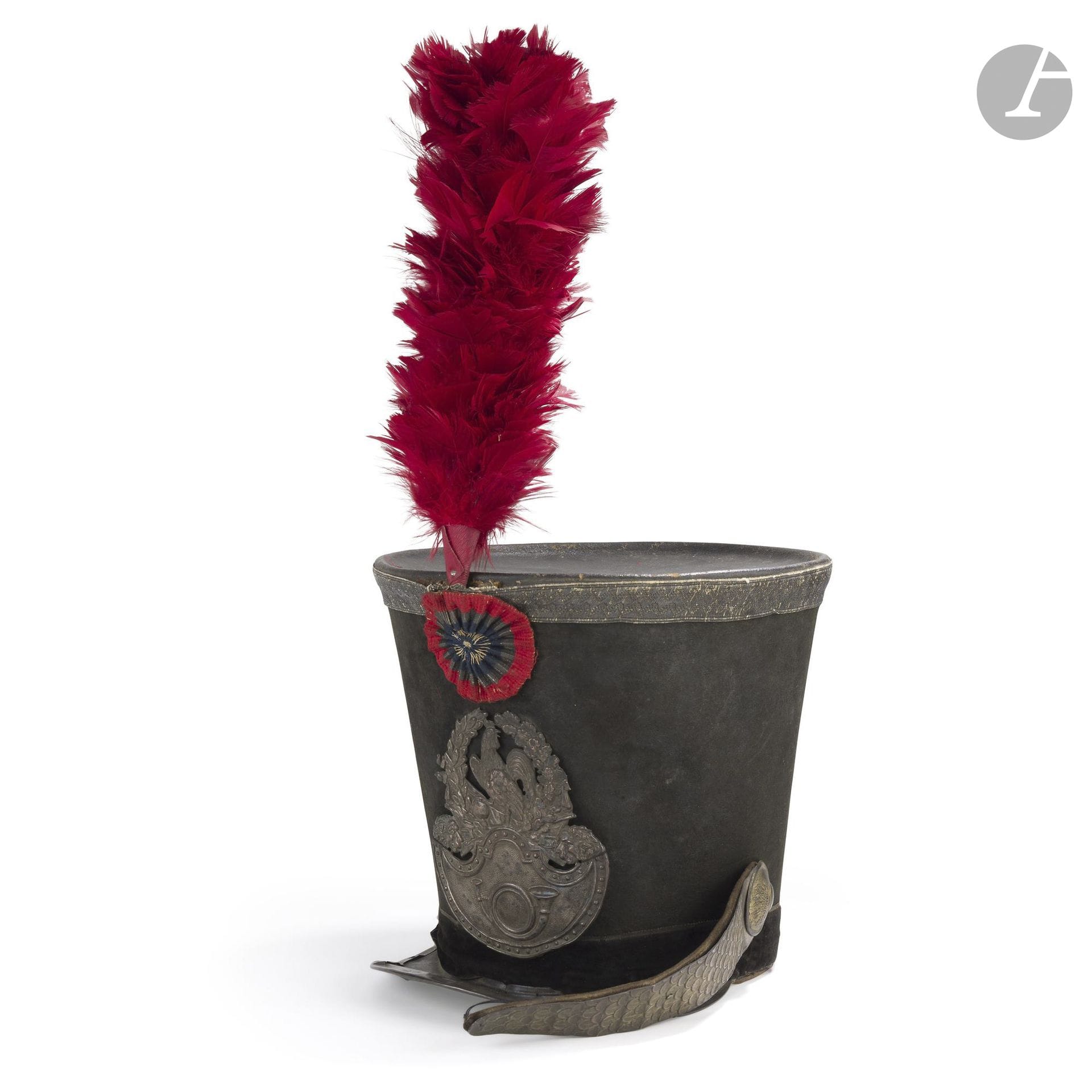 Shako de chasseur à pied de la garde nationale.
Fût en feutre taupé. Galon à lézardes en passementerie argentée, bourdalou en velours noir. Plaque au coq et au cor, jugulaires à fausses écailles doublées de velours et jonc (accident) en cuivre argenté. Visière en cuir verni. Cocarde tricolore brodée. Avec un plumet écarlate.
A.B.E. Époque Monarchie de Juillet.
