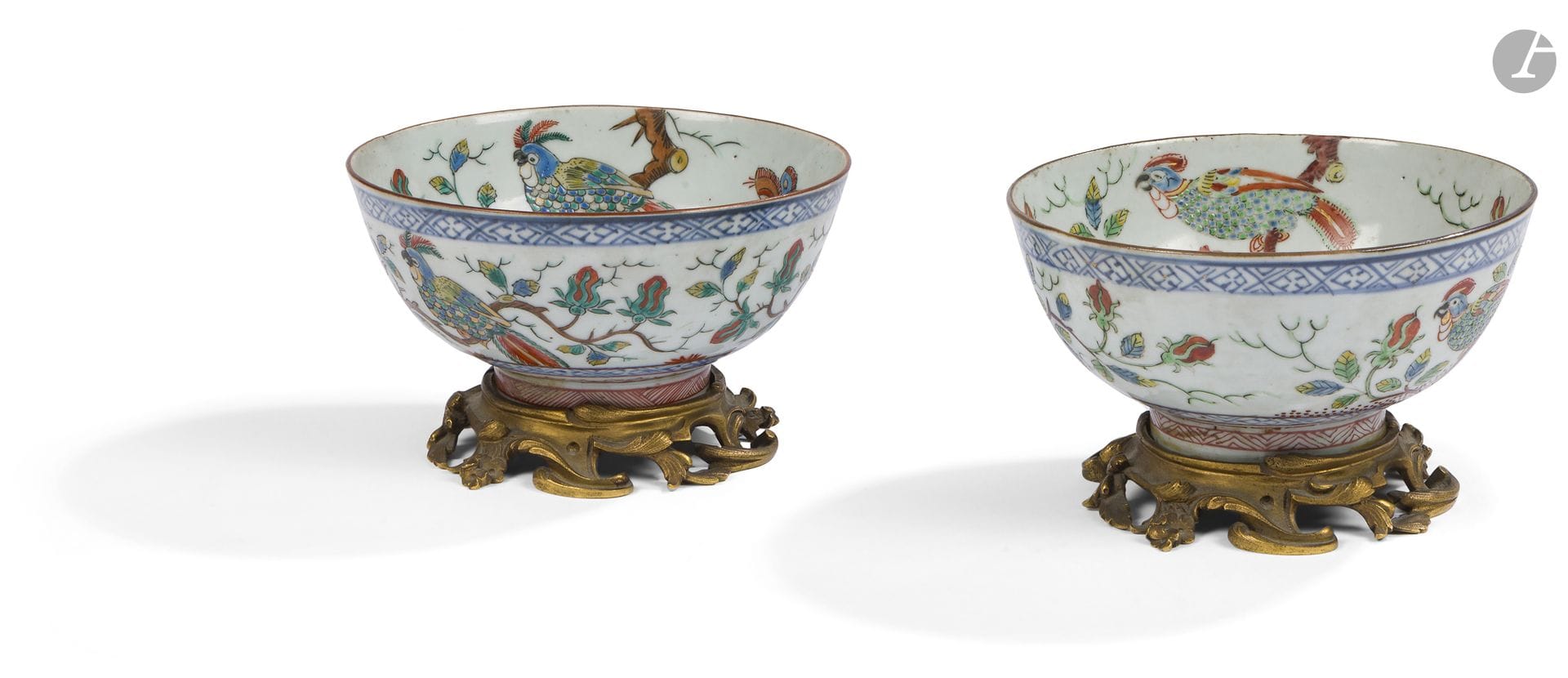Chine décoré en Hollande
Paire de bols en porcelaine à décor polychrome de perroquets sur des arbustes fleuris et galons.
XVIIIe siècle.
Base en bronze doré de style rocaille. 
H. : 9 cm, D. : 14 cm
Fêlure à l'un.