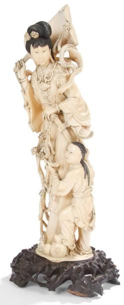 CHINE - XXe siècle
Groupe en ivoire, jeune femme debout tenant un éventail rigide, accompagnée d?un garçon lui tendant une branche de pivoines. H.: 35 cm