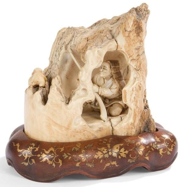 JAPON - Epoque MEIJI (1868 - 1912)
Okimono en ivoire, chasseur se cachant dans une grotte. H.: 9 cm Socle en bois laqué
