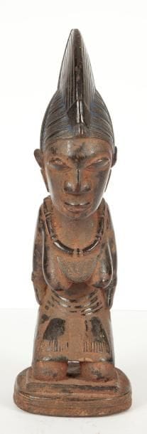 YOROUBA (Nigéria) Statuette agenouillée. Bois à fine patine brun rouge. Rehaut de d'ocre rouge et de bleu de lessive. Hauteur: 31 cm