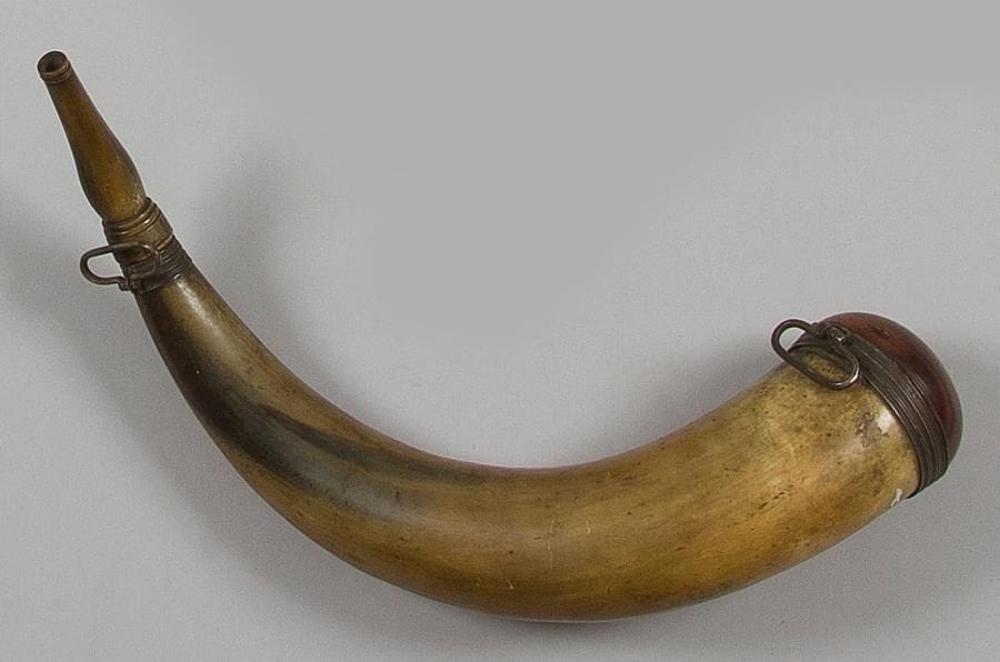 Grande corne à poudre d'artillerie de marine à deux suspentes, en corne de buffle avec bec rond en suite. Fond en bois patiné. Garnitures en métal blanc. B.E. XVIIIe siècle.