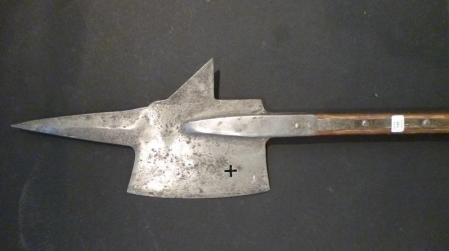 Hallebarde du type Zurich. Fers de hache poinçonnés, à croix à jours, à pointe poinçonnée sur le dos. Prolongée d'un large fer d'estoc à arête médiane, montée sur douilles à pans à deux longues attelles maintenues par six clous. De style XVIIe siècle, fabriquée au XIXe siècle. Montée sur une hampe en bois postérieure.