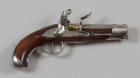 Pistolet à silex de gendarmerie modèle an IX. Canon rond à méplats au tonnerre, avec marquages. Queue de culasse gravée «Mle An 9». Platine à corps plat gravée «Maubeuge Manufre Imple» à corps plat et chien à corps rond. Garnitures en fer poinçonné. Crosse en noyer (enture à l'avant du fût). Baguette clou en fer. B.E. Époque Premier Empire.