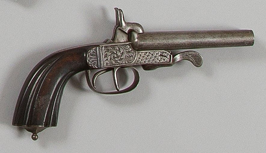 Pistolet à broche, deux coups, calibre 12 mm. Canons ronds en table basculant vers le bas. Coffre ciselé de feuillages. Bascule, clé et pontet à décor quadrillé. Crosse en noyer sculpté. B.E. Vers 1860.