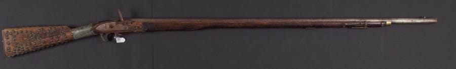 Long fusil à silex africain. Canon rond. Platine à corps plat (manque le chien). Crosse en noyer décoré de clous en laiton. XIXe siècle.