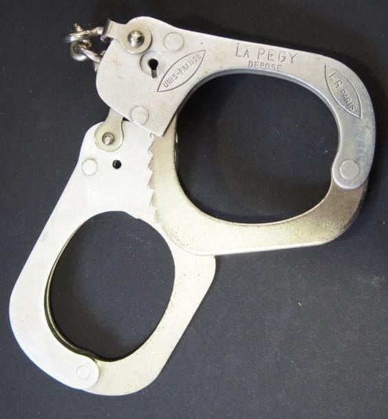 Paire de menottes réglementaires «La Pegy déposé Unis France». En aluminium et fer (manque la clé).