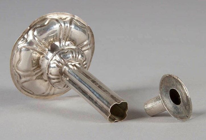 Bougeoir miniature en argent repoussé, la base ronde, le fût en gaine, la bobèche ronde. Poinçon au cygne et poinçon d'impôt pour les ouvrages de fabrication locale aux Pays-Bas. Trace de poinçon XVIII. Petit accident à la bordure. Probablement Pays-Bas XVIIIe siècle. Poids: 28 g - Haut.: 7,3 cm