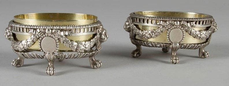 Paire de salières ovales en argent fondu ciselé, intérieur en vermeil amovible, à décor de guirlandes et mufles de lion. Poinçon minerve. Poids: 353 g