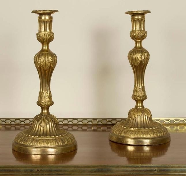 Paire de flambeaux en bronze doré, le fût en balustre à décor de feuilles d'acanthe et canaux, reposant sur une base circulaire à frise de feuillages. Époque Louis XVI H.: 31 cm