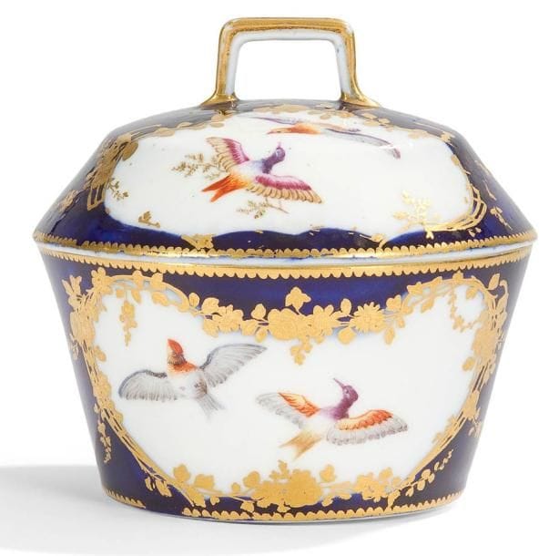 VINCENNES
Pot à sucre couvert nommé pot à sucre à la Reine à décor polychrome d'oiseaux en vol dans des réserves cernées de motifs de treillage et branches fleuries en or sur fond bleu lapis. Marqué: LL entrelacés, lettre-date A pour 1753-54. XVIIIe siècle, année 1753-54. H.: 12 cm Usures d'or sur le couvercle